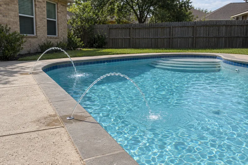 Two thin water arcs from deck jets landing in a pool