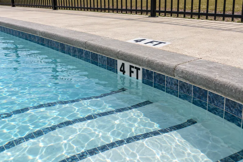 Depth marker tiles reading 4 FT at the edge of a community pool