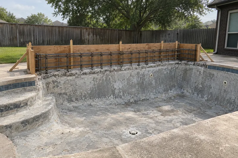 Drained pool mid-remodel with framing for a raised back wall