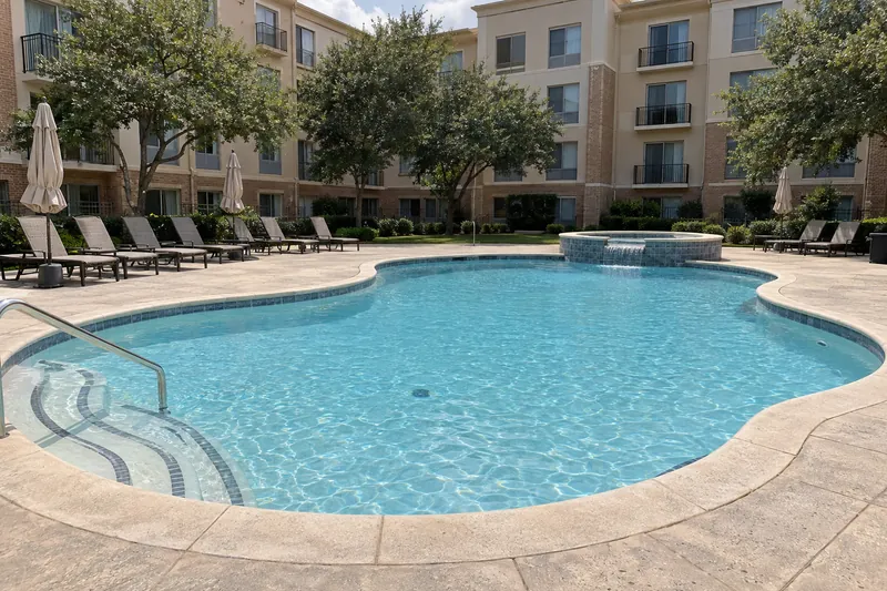 Freshly resurfaced hotel pool with lounge chairs beside a hotel wing