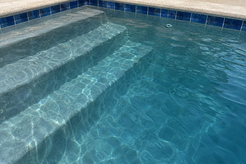 Medium-gray plaster finish turning pool water a deep teal